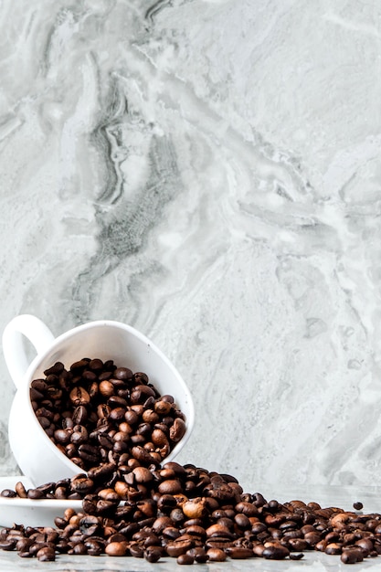 Caffè nero in tazza e chicchi di caffè su fondo di marmo.