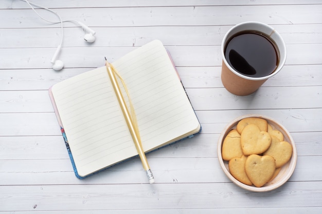 Caffè nero in un bicchiere di carta e biscotti a forma di cuori su uno sfondo bianco. spazio copia piatta laici, vista dall'alto.