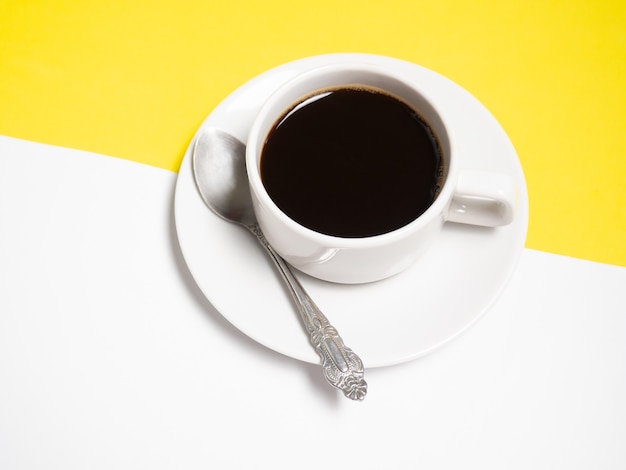 Caffè nero in una tazza bianca su sfondo giallo, copia spazio