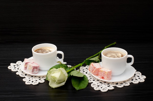 Caffè per due con dolci orientali, una rosa bianca su sfondo nero