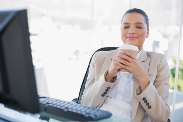 Caffè sentente l&#39;odore della donna di affari specializzata felice