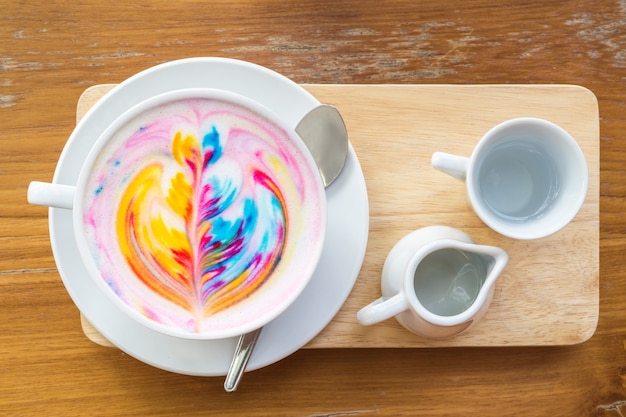 Caffè variopinto del latte dell&#39;arcobaleno in tazza bianca sulla tavola di legno con lo spazio della copia per testo o progettazione