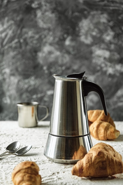 caffettiera in acciaio geyser su sfondo grigio foto di caffè e croissant luce tradizionale br