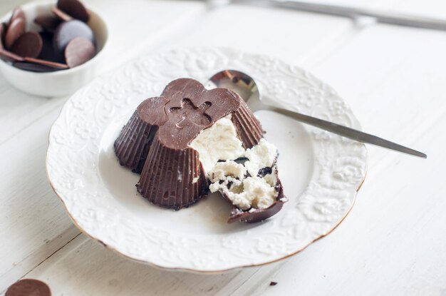 Cagliata di formaggio glassata fatta in casa con cioccolato e tazza di caffè colazione dolce sul tavolo bianco