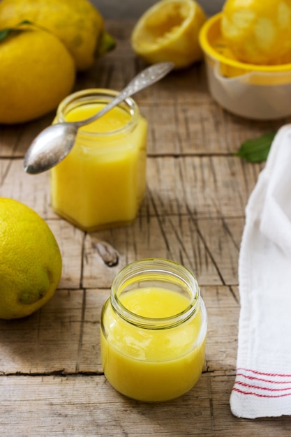 Cagliata di limone fatta in casa con barattoli e limoni su fondo di legno