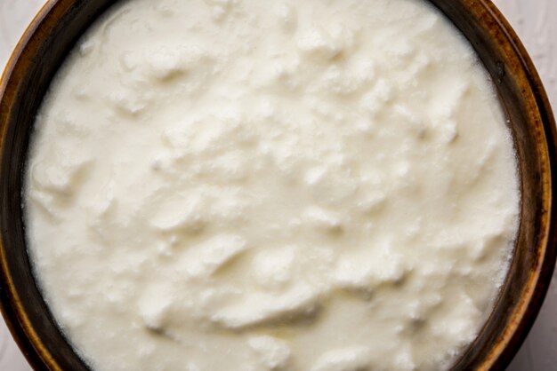 Cagliata normale o yogurt o Dahi in hindi, servita in una ciotola su uno sfondo lunatico. Messa a fuoco selettiva