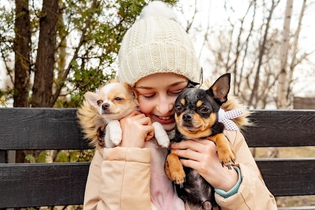 Cagna. Ragazza adolescente con due cani chihuahua in braccio. Cani vestiti. amico proprietario cucciolo.