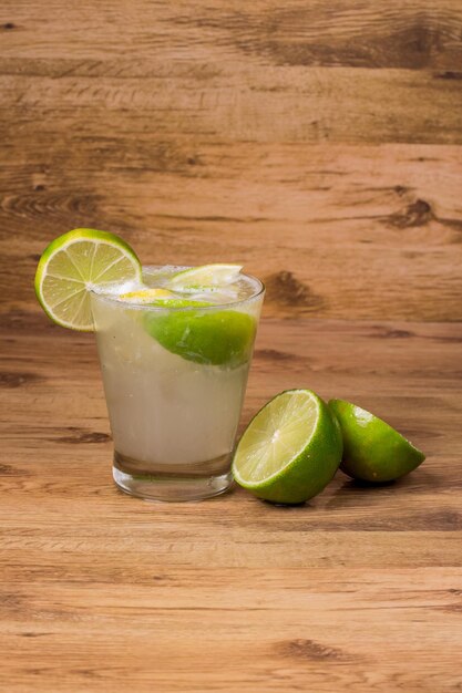 Caipirinha Cocktail nazionale brasiliano realizzato con liquore di canna cachaca e limone su sfondo di legno