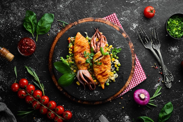 Calamari al forno con riso e verdure su una lastra di pietra nera Frutti di mare Vista dall'alto Spazio libero per la copia