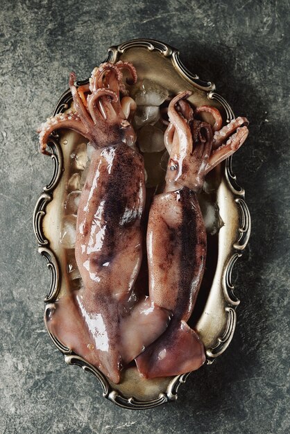 Calamari crudi freschi su un piatto di cupronichel