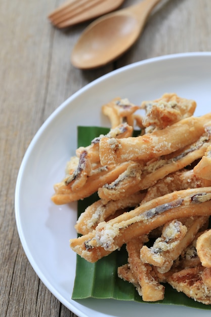 Calamaro fritto di frutti di mare tailandesi nel piatto bianco sul pavimento di legno.