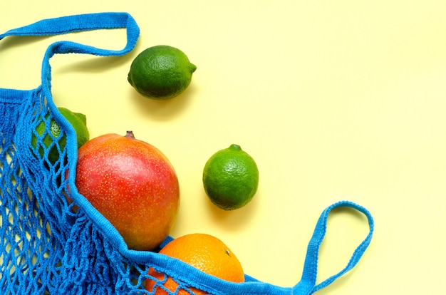 Calce esotica di agrumi tropicali esotici e succosi di mango arancione lime in un sacchetto di stringa blu. concetto di zero rifiuti.