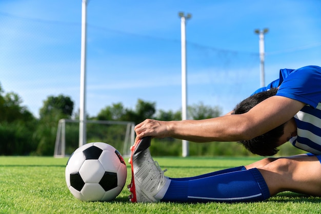 Calciatore di calcio che si allunga durante il riscaldamento prima di calciare la palla nella partita di campionato nello stadio con un sano concetto di sport