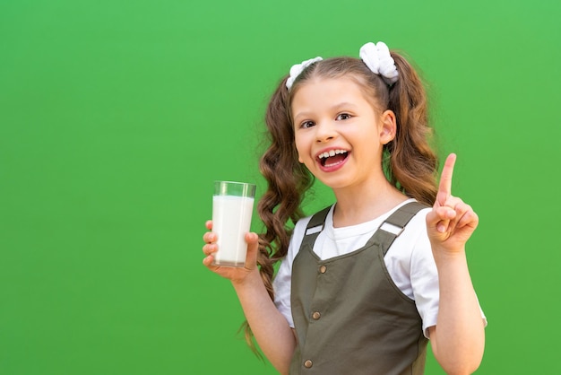 Calcio per il corpo del bambino. La ragazza beve un bicchiere di latte a colazione.