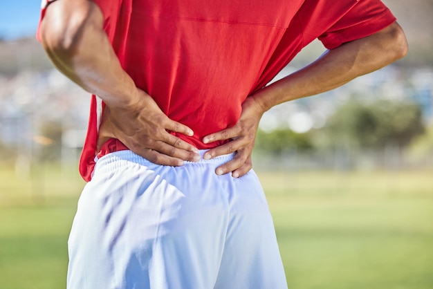 Calcio sul campo e uomo con infortunio alla schiena nel torneo di gioco con infiammazione del dolore e mal di schiena Atleta di calcio e incidente in partita con il giocatore che tiene il muscolo del corpo per alleviare la pressione