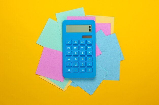 Calcolatrice con pezzi di carta memo su un giallo
