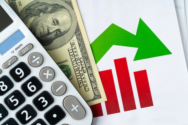 Calcolatrice con pila di dollari americani e grafico