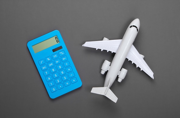 Calcolatrice e figurina di un aereo passeggeri su un grigio. Calcolo del costo del viaggio aereo.