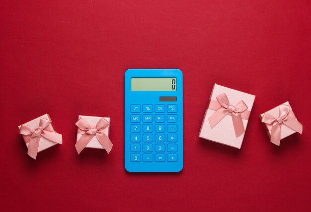 Calcolatrice e scatole regalo con fiocco rosso. Calcolo del valore del regalo.