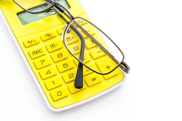 Calcolatrice gialla semplice con occhiali da lettura su sfondo bianco.