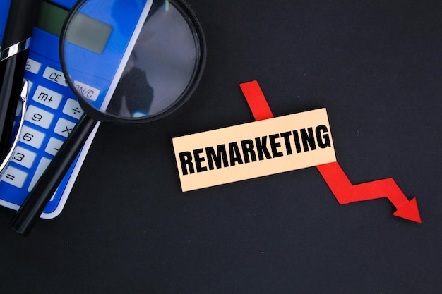 Calcolatrice, lupa e penna con la parola remarketing concetto di marketing