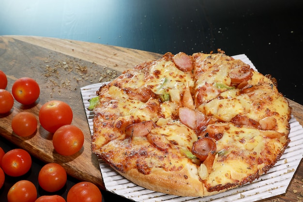 Calda fetta di pizza fatta in casa con formaggio fuso e salsiccia sul pomodoro superiore e piccolo.