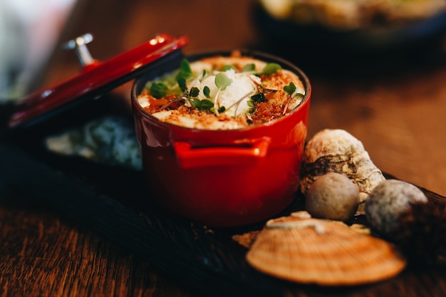 Calda julienne con frutti di mare in un vaso rosso