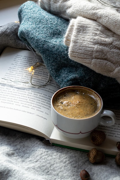 Caldo maglione lavorato a maglia, caffè nero caldo e un libro interessante per leggere intime serate