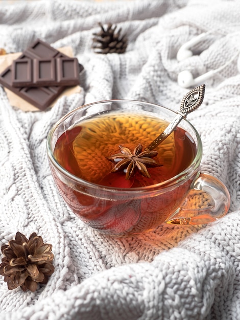 Caldo maglione lavorato a maglia, una tazza di tè caldo con cioccolato e decorazioni invernali,