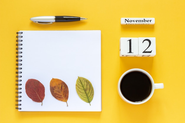 Calendario 12 novembre tazza di caffè, blocco note con penna e foglia gialla