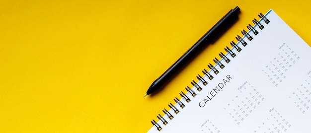 Calendario bianco e penna pulita su sfondo giallo con spazio per la copia