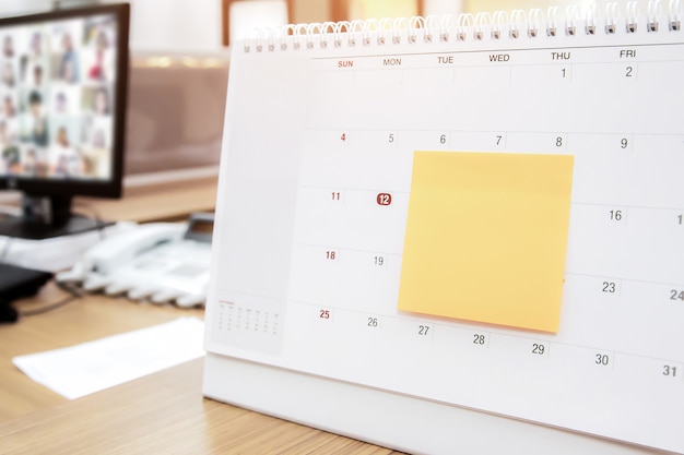 Calendario con nota cartacea sulla scrivania in ufficio per pianificatore di eventi.