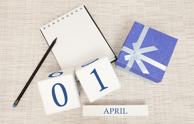 Calendario con testo blu e numeri alla moda per il 1 ° aprile e un regalo in una scatola.