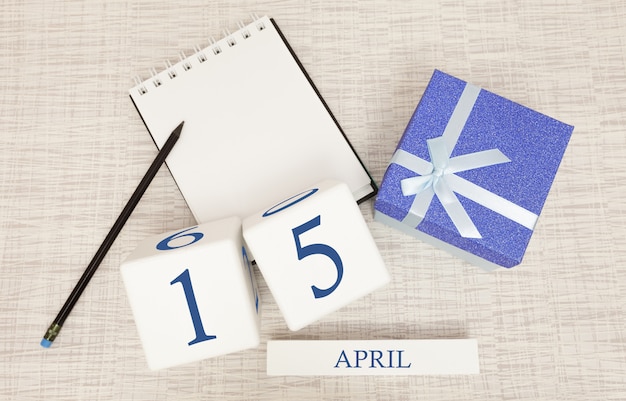 Calendario con testo blu e numeri alla moda per il 15 aprile e un regalo in una scatola.