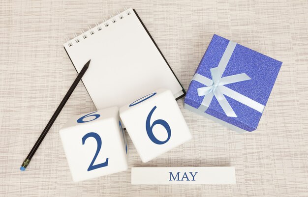 Calendario con testo blu e numeri alla moda per il 26 maggio e un regalo in una scatola.