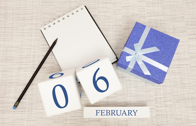 Calendario con testo blu e numeri alla moda per il 6 febbraio e un regalo in una scatola.