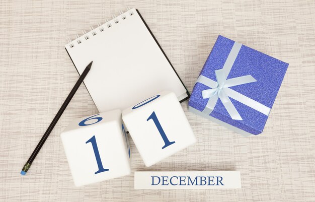 Calendario cubo dell'11 dicembre e confezione regalo, vicino a un quaderno con una matita