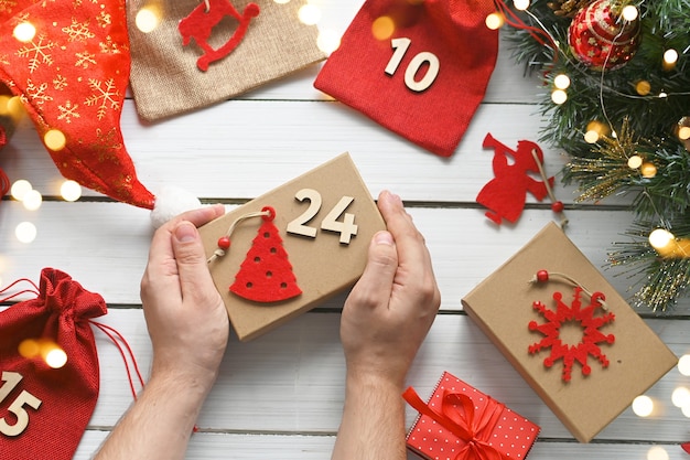 Calendario dell'avvento Buon Natale Le mani di un uomo tengono una scatola regalo in carta kraft