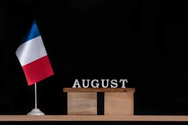 Calendario di agosto in legno con bandiera francese su sfondo nero Vacanze in Francia nel mese di agosto