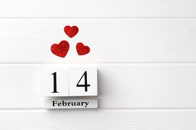 Calendario in legno 14 febbraio con cuori rossi su fondo di legno bianco