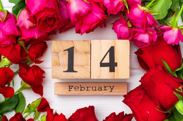 Calendario in legno 14 febbraio e rose sul piatto bianco laici