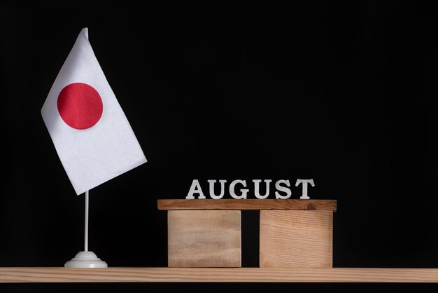 Calendario in legno di agosto con bandiera del Giappone su sfondo nero Date del Giappone nel mese di agosto