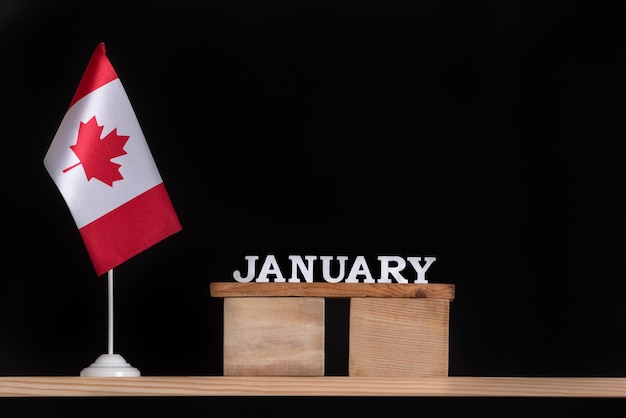 Calendario in legno di gennaio con bandiera canadese su uno spazio nero. Vacanze del Canada a gennaio.