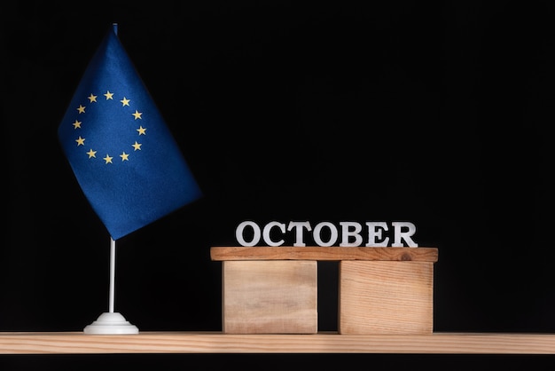 Calendario in legno di ottobre con bandiera UE su superficie nera. Unione Europea Date di ottobre.