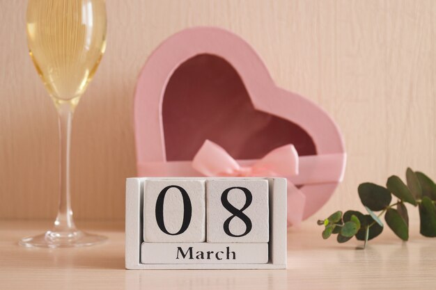 Calendario marzo in legno, un bicchiere di champagne e una confezione regalo a forma di cuore