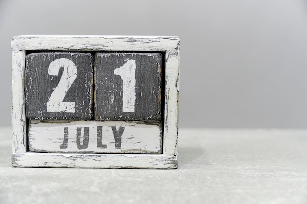 Calendario per il 21 luglio fatto di cubi di legno su sfondo grigioCon uno spazio vuoto per il testo