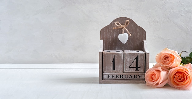 Calendario perpetuo in legno con data 14 febbraio e bouquet di rose. Simboli San Valentino. Cartolina. Spazio libero per i tuoi progetti migliori.