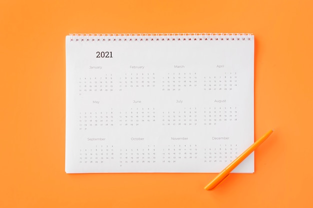 Calendario pianificatore piatto laici su sfondo arancione