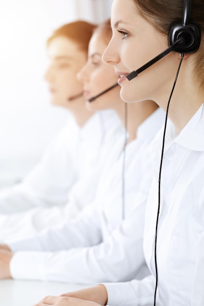 Call center. Bella giovane donna che utilizza l'auricolare e il computer per aiutare i clienti nell'ufficio soleggiato. Concetto di affari.