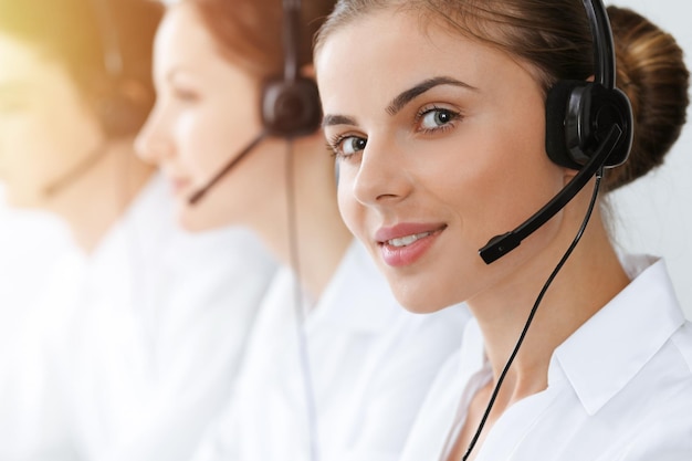 Call center. Bella giovane donna che utilizza l'auricolare e il computer per aiutare i clienti nell'ufficio soleggiato. Concetto di affari.